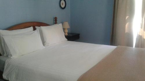 a white bed with white pillows in a bedroom at Whitsunday Cane Cutters Cottage in Cannon Valley