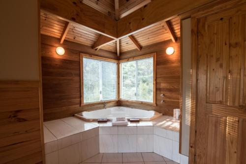 a bathroom with a tub in a room with wooden walls at Cape Howe Cottages in Lowlands