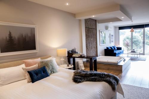 a bedroom with a large white bed and a living room at Polperro Villas in Red Hill