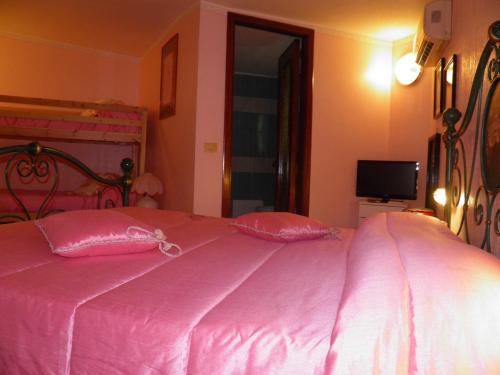 a pink bed with two pink pillows in a bedroom at Parco Delle Tre Fontane in Nicolosi