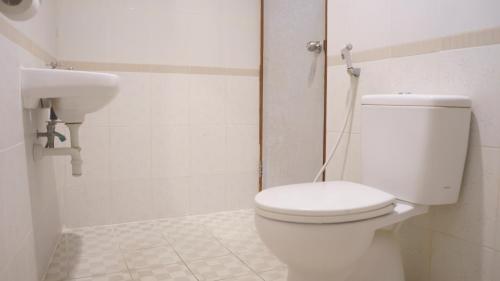 a white bathroom with a toilet and a sink at Pondok Mirah in Kuta