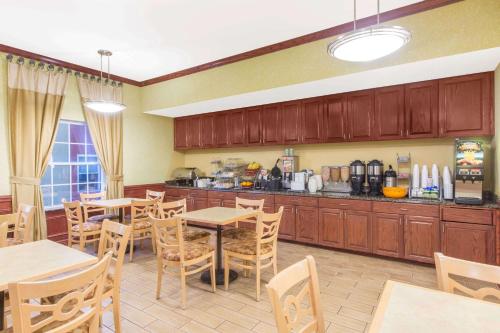 コーパスクリスティにあるHawthorn Extended Stay by Wyndham Corpus Christi Padre Isleのキッチン(木製のキャビネット、テーブル、椅子付)