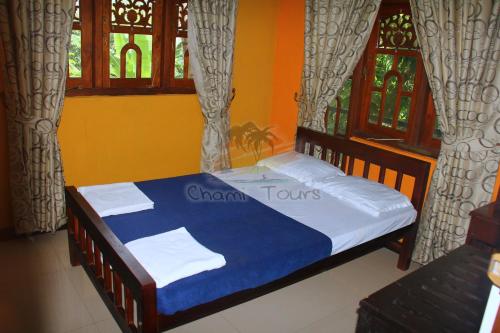 a bedroom with a bed with blue and white sheets and windows at Airport Tourist Hostel in Katunayake