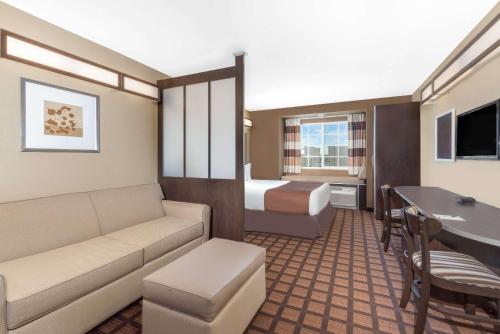 a hotel room with a couch and a bed at Microtel Inn & Suites by Wyndham in Midland