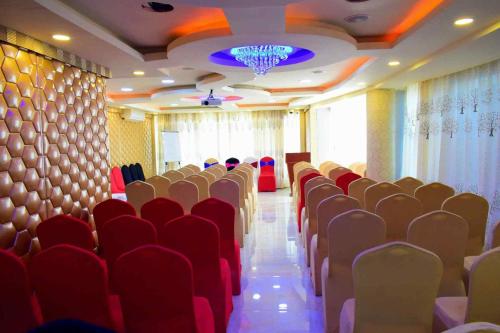 a conference room with red chairs and a chandelier at Hyders Park The Business Hotel in Thanjāvūr