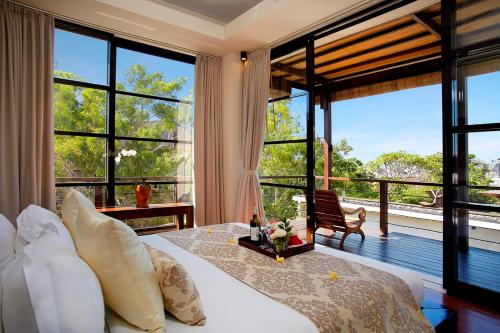 a bedroom with a large bed and large windows at Temple Hill Residence Villa in Jimbaran