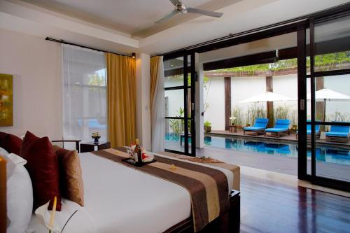 a bedroom with a large bed and a swimming pool at Temple Hill Residence Villa in Jimbaran
