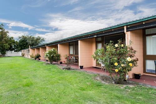 a row of buildings with trees and bushes at Blenheim Road Motor Lodge in Christchurch