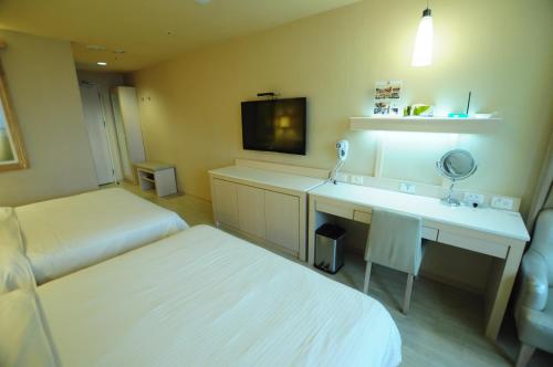 Habitación de hotel con cama y escritorio con espejo. en Kindness Hotel - Kaohsiung Guang Rong Pier, en Kaohsiung