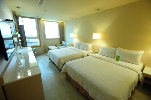 a hotel room with two beds and a couch at Kindness Hotel - Kaohsiung Guang Rong Pier in Kaohsiung