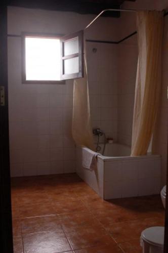 a bathroom with a bath tub and a window at GBH Casas Fimbapaire in La Oliva