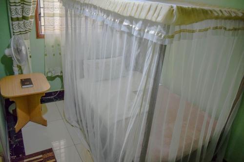 a white shower curtain in a bathroom with a table at The Joy Hotel in Voi