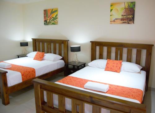 a bedroom with two beds with orange and white sheets at Samoana Boutique Hotel in Apia