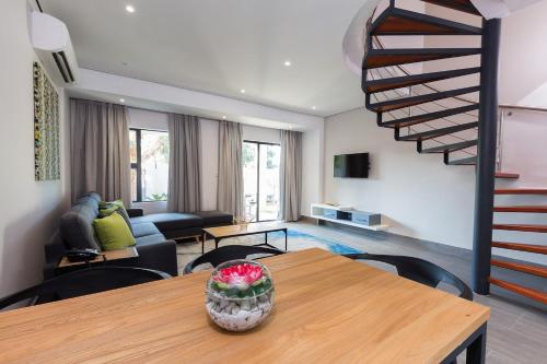 a living room with a table and a spiral staircase at City Mews On Independence in Gaborone