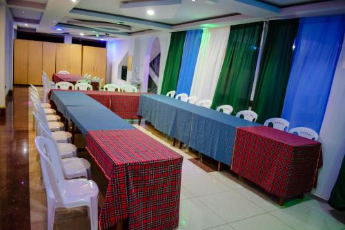 a row of tables and white chairs in a room at The Joy Hotel in Voi