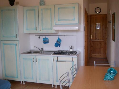 una cucina con armadi blu, lavandino e tavolo di Il Geranio a Badesi