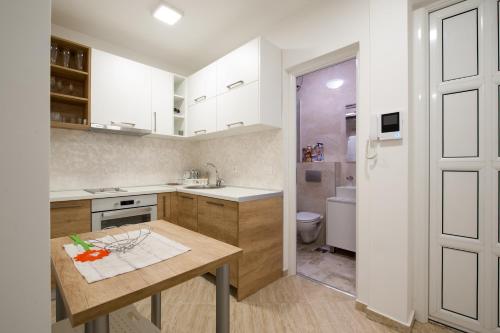 a kitchen with white cabinets and a wooden table at Apartments Mia in Sveti Stefan