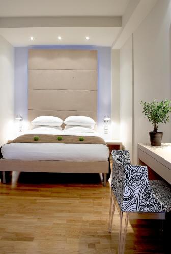 a bedroom with a large bed and a chair at Domotel Olympia in Thessaloniki