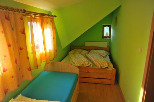 ein grünes Schlafzimmer mit einem Bett und einem Fenster in der Unterkunft Apartmá u Hovorků in Županovice