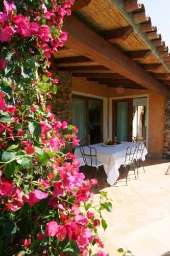 a table with chairs and pink flowers on a patio at Villa Myrtos - 300mt dal mare in Chia