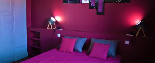 a purple bedroom with a bed with pink sheets and pillows at L'Iliade - Chambres d'hôtes - B&B à Bouzy in Bouzy