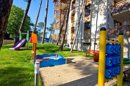 un parque infantil frente a un edificio con tobogán en Mi Casa Holidays Rezydencja Park Rodzinna, en Mielno