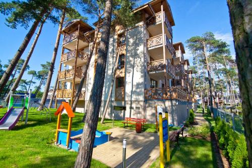 un edificio de apartamentos con un parque infantil delante de él en Mi Casa Holidays Rezydencja Park Rodzinna, en Mielno