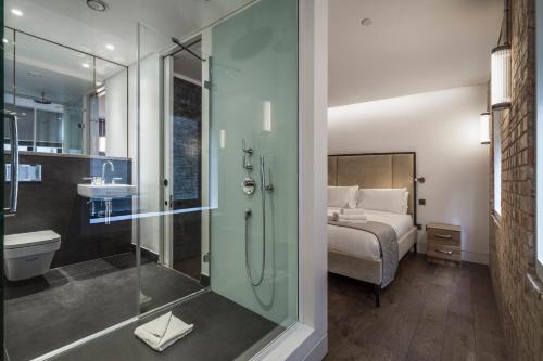 uma casa de banho com um chuveiro e um quarto com uma cama em Soho One em Londres