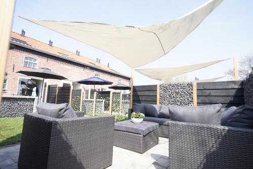 a patio with wicker chairs and umbrellas at 't Veldehof in Domburg