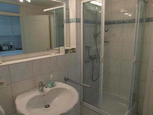 La salle de bains est pourvue d'un lavabo et d'une douche avec une porte en verre. dans l'établissement Haus-Metropol-Neues-Kurzentrum-Appartement-38, à Westerland