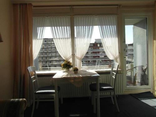 une table et des chaises dans une chambre avec une grande fenêtre dans l'établissement Haus-Metropol-Neues-Kurzentrum-Appartement-38, à Westerland