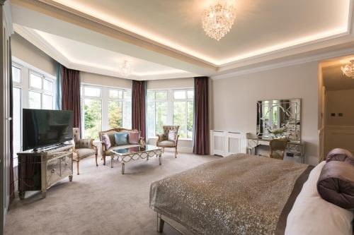 a bedroom with a bed and a tv and a living room at Fitzgeralds Woodlands House Hotel in Adare