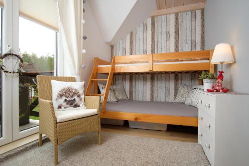 a small bedroom with a bunk bed and a chair at Apartament Makowe Pola in Żarnowska