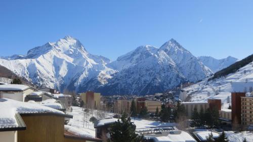 a city with snow covered mountains in the background at Les deux Alpes studio in Les Deux Alpes