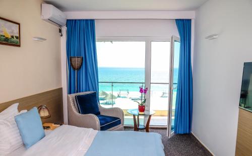 um quarto de hotel com uma cama e uma varanda com o oceano em Alcor Beach Hotel em Mamaia