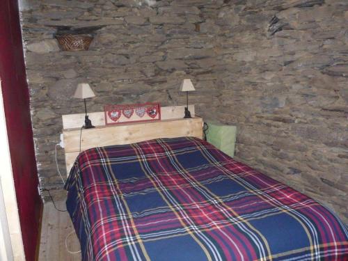 a bedroom with a bed with a stone wall at Laoujou in Auzat