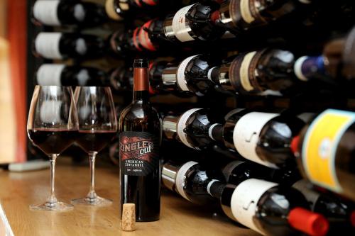 two glasses of wine in front of a wall of wine bottles at Hotel Amerika in Hobro