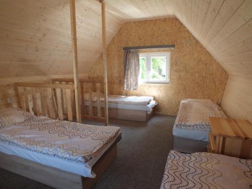 a attic room with three beds and a window at Chaty - Resort AQUA MARIA in Veľaty
