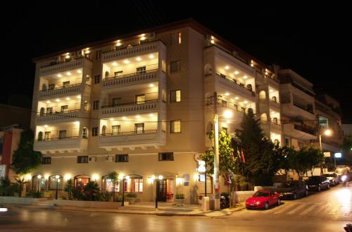 Un grand bâtiment blanc avec des lumières allumées la nuit dans l'établissement Elina Hotel Apartments, à Réthymnon