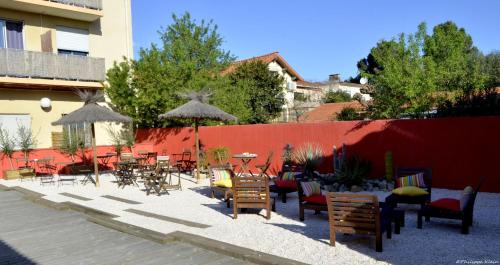 een patio met stoelen, tafels en parasols bij Hôtel Les Mimosas in Argelès-sur-Mer