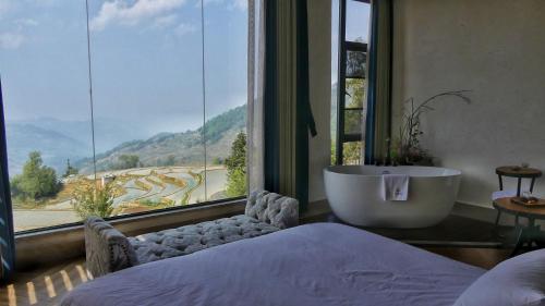 a bedroom with a bath tub and a large window at The Twelve Manor•Terraces Lodge in Yuanyang