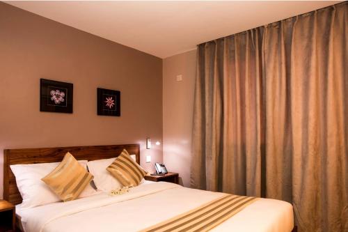 a bedroom with a bed and a window with curtains at Venus Premier Hotel in Arusha