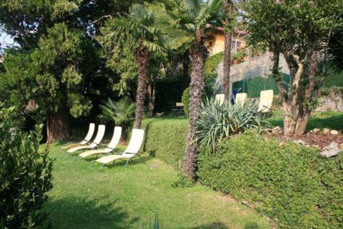 a group of white lounge chairs in a yard at Hotel Excelsior Splendide in Bellagio