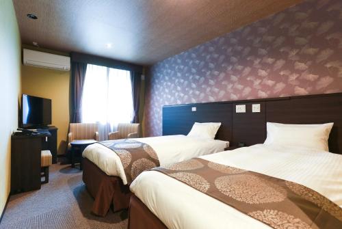 a hotel room with two beds and a television at TABINO HOTEL Hida Takayama in Takayama