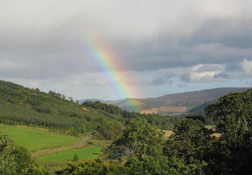 a rainbow in the sky over a green field at Torridon Guest House in Inverness