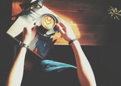 a person is holding a cup of coffee at Wheeler Bed &Bike in Bangsaen