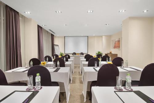 a conference room with white tables and black chairs at Mercure Hanoi La Gare Hotel in Hanoi