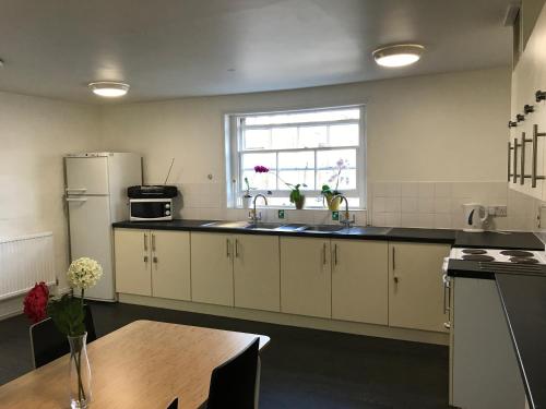 een keuken met een wastafel, een koelkast en een tafel bij Railton House (Paddington) in Londen