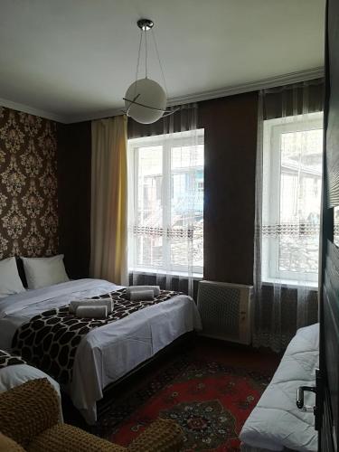 a bedroom with two beds and two windows at Nikoloz Guesthouse in Stepantsminda