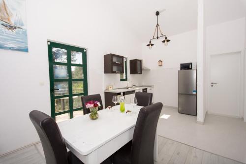 a kitchen with a white table with chairs and a refrigerator at Guesthouse Vakans in Slatine